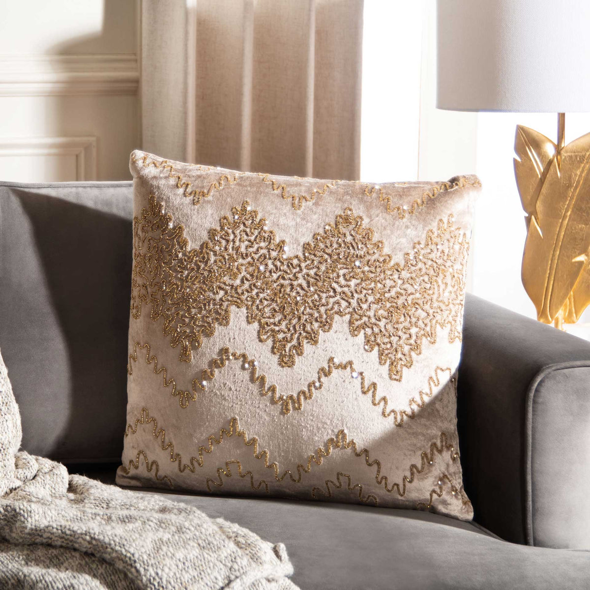 Gold embellished motifs and zigzag accents lend a warm glow to this soft neutral pillow.