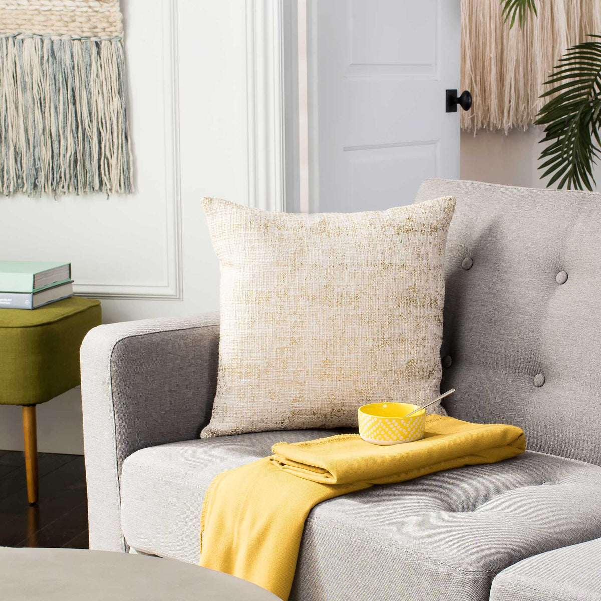 A gold-speckled cream pillow brings soft texture and warmth to a gray lounge chair