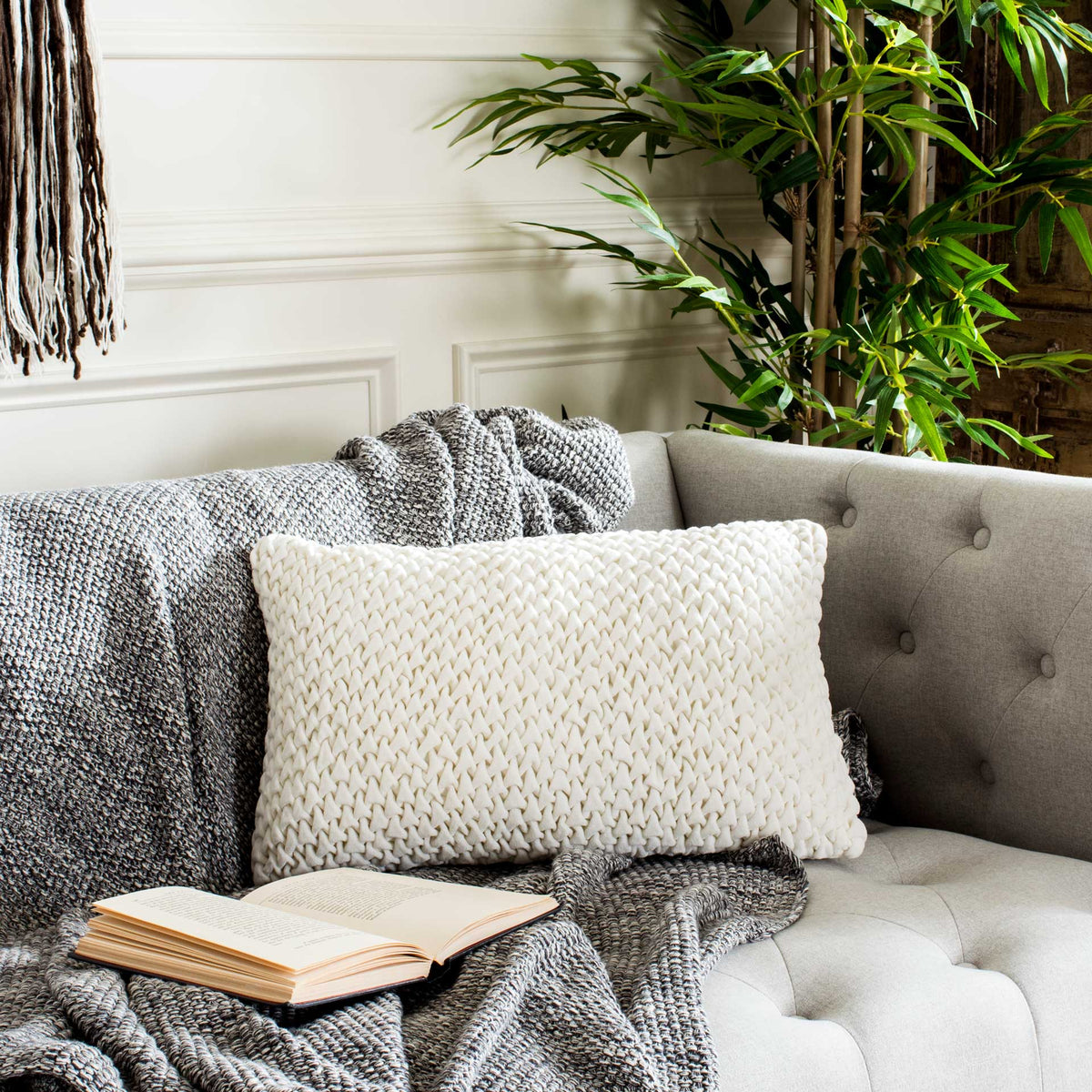 Cream rectangular pillow layers woven texture onto a tufted sofa.
