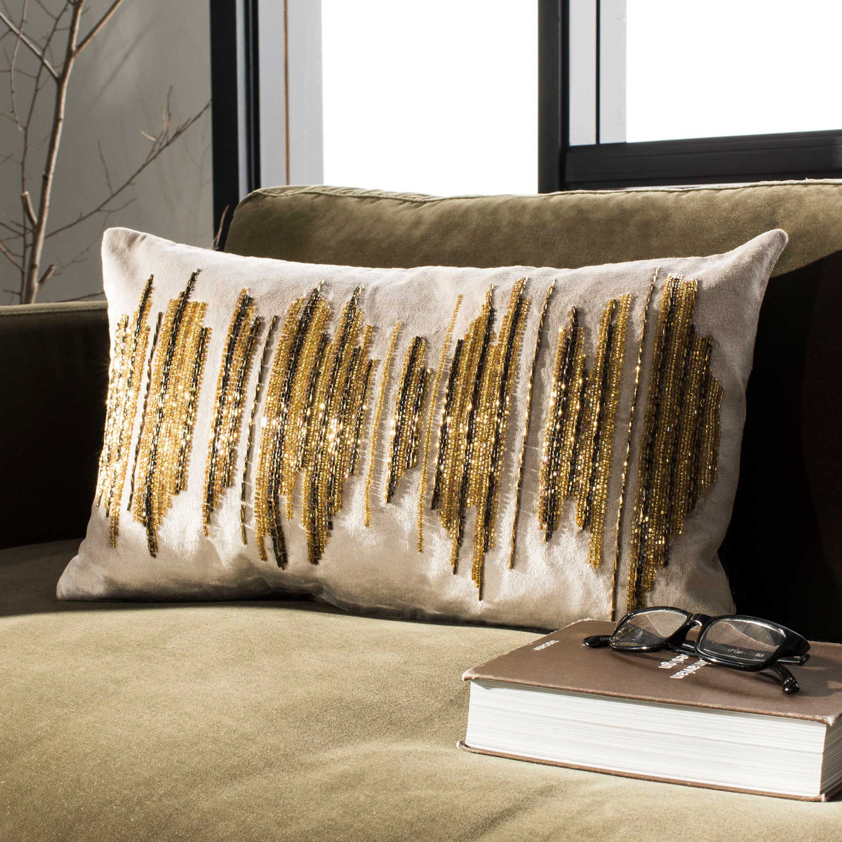Shimmering gold and dark beaded streaks lend texture to a beige lumbar pillow.