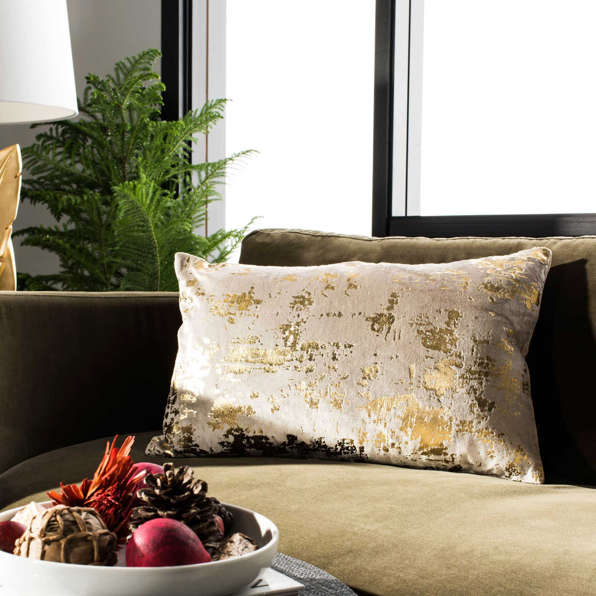Beige and gold lumbar pillow adds a warm metallic shimmer to a cushioned sofa.