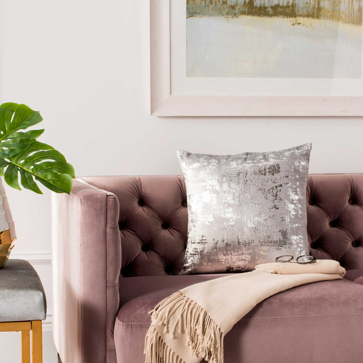 Shimmering silver and gray square pillow adds a bright accent to a tufted mauve sofa.