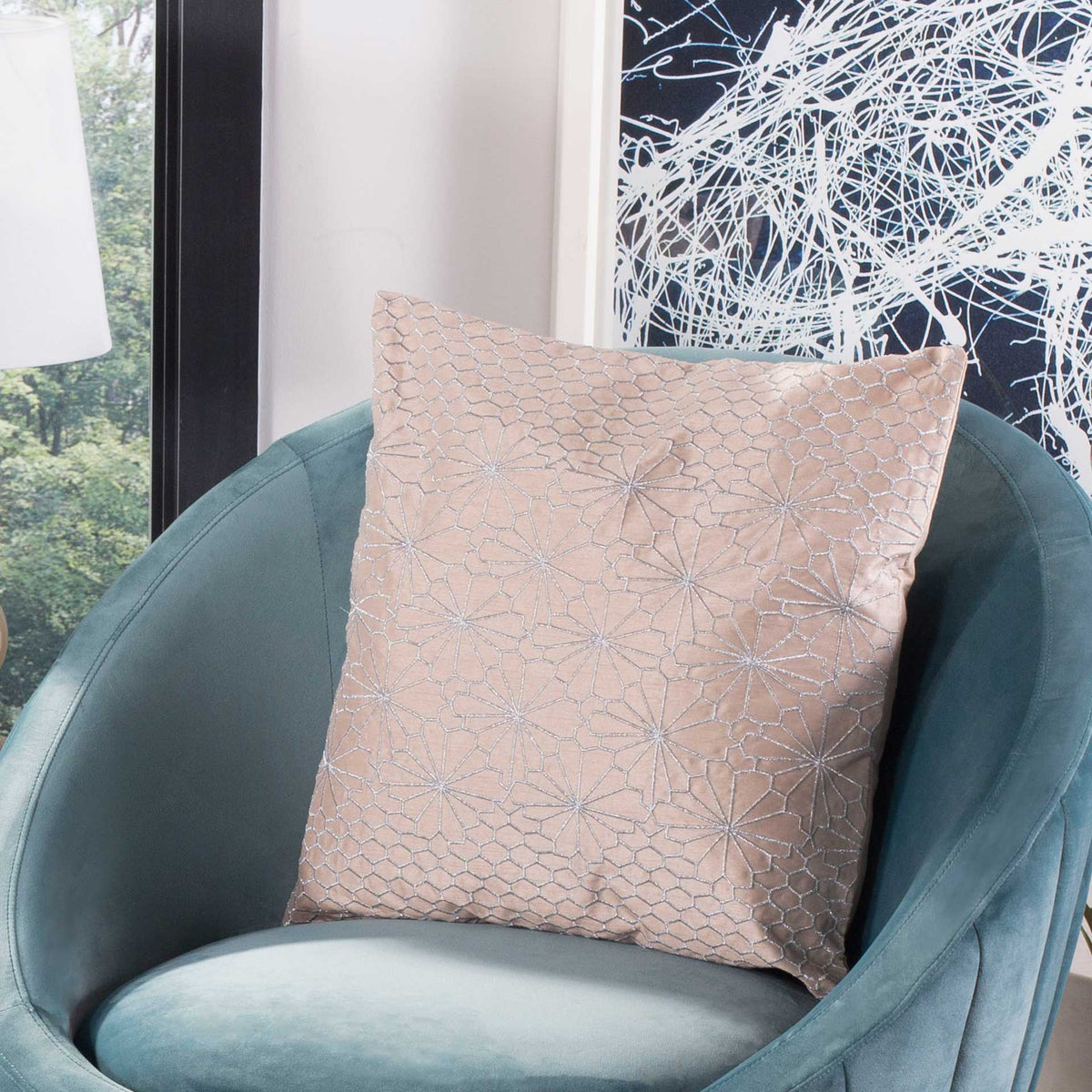A blush embroidered pillow brings delicate geometric pattern to a teal accent chair