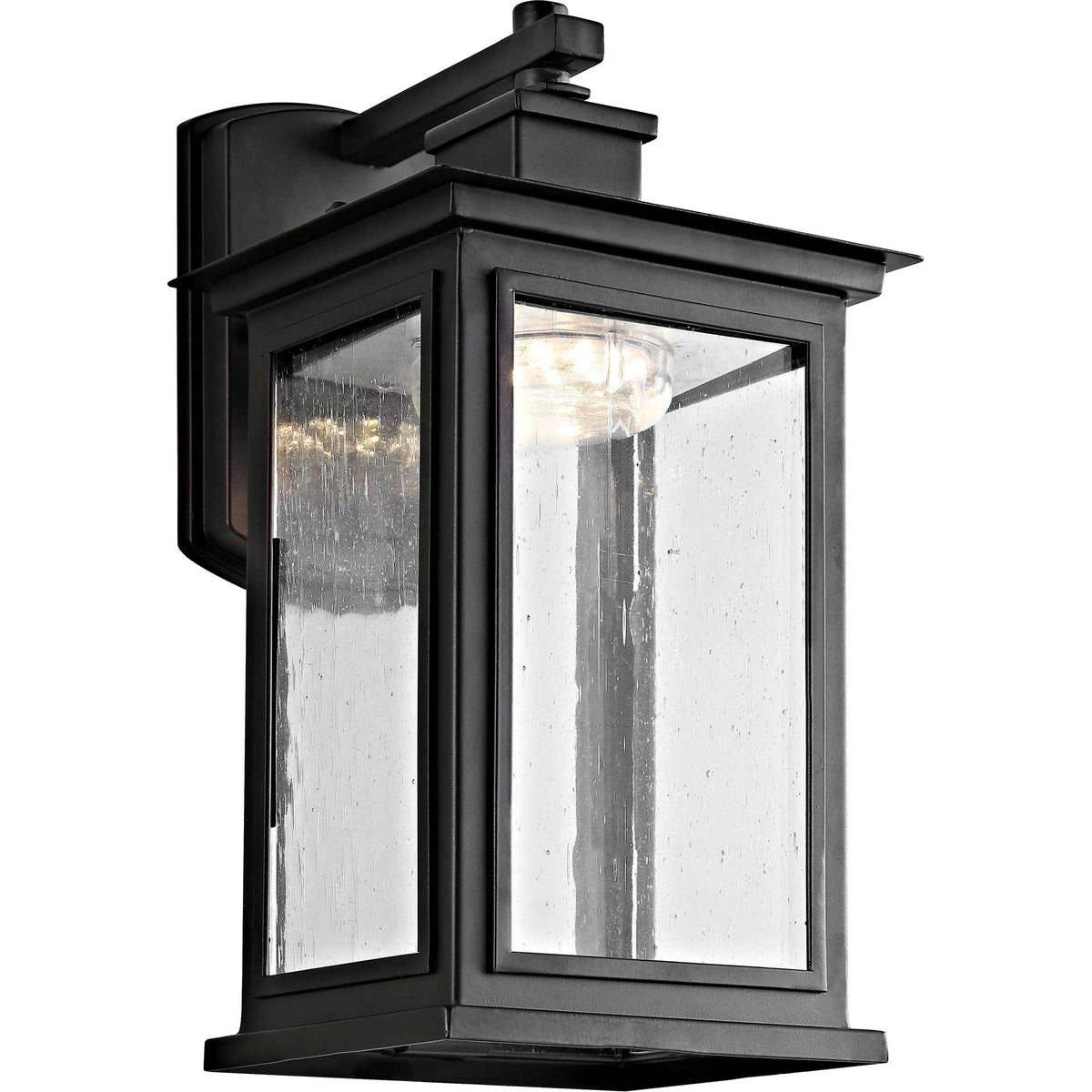 Warm light shines through the seeded glass of a bronze outdoor wall lantern