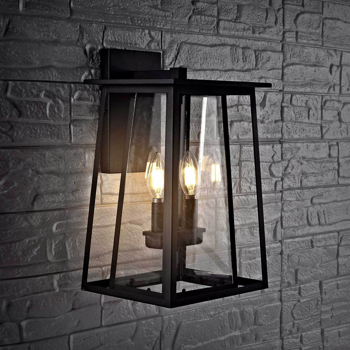 Candle-style bulbs glow inside a black glass lantern against a dark stone wall