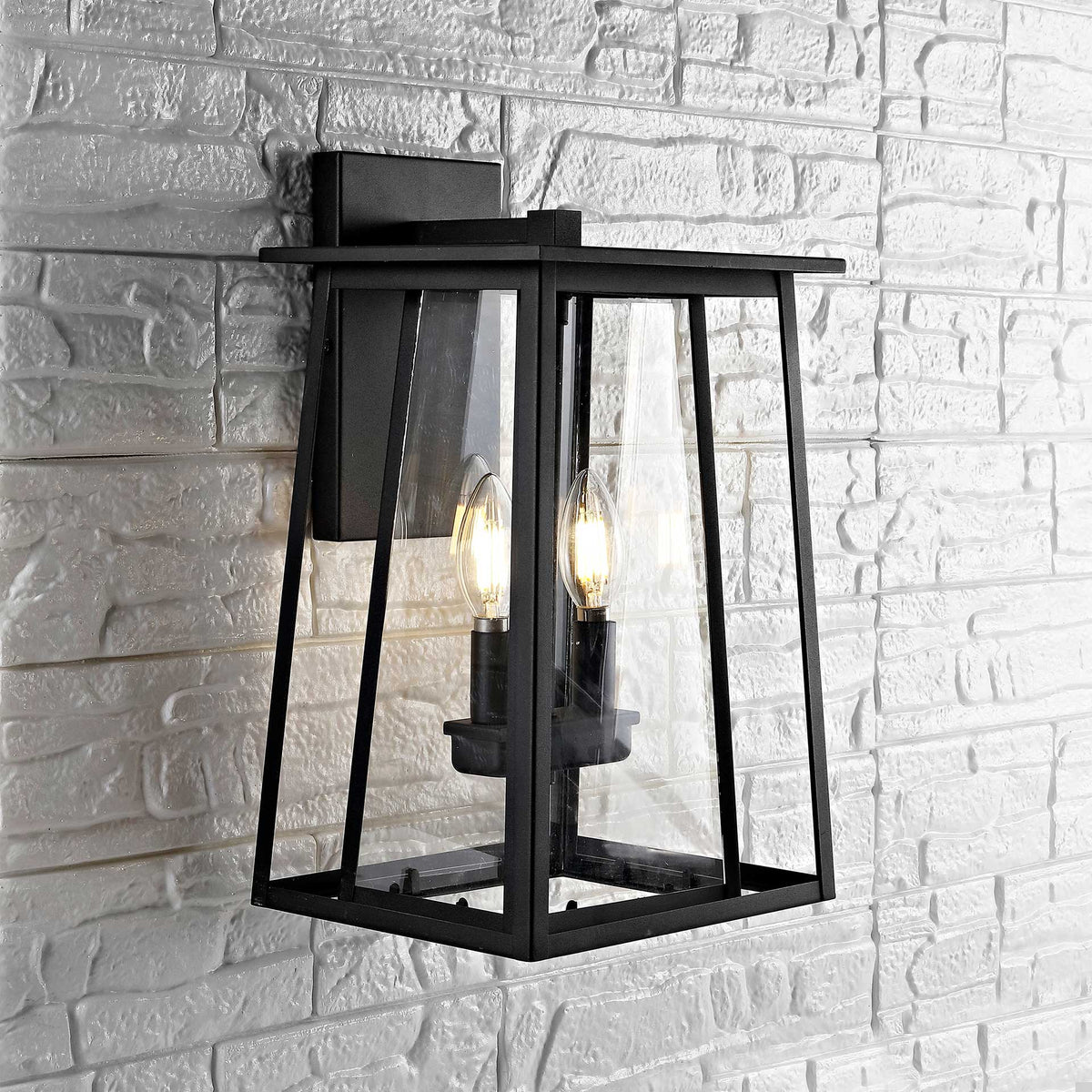 Black wall lantern adds warm light and clear glass detail to a pale stone wall