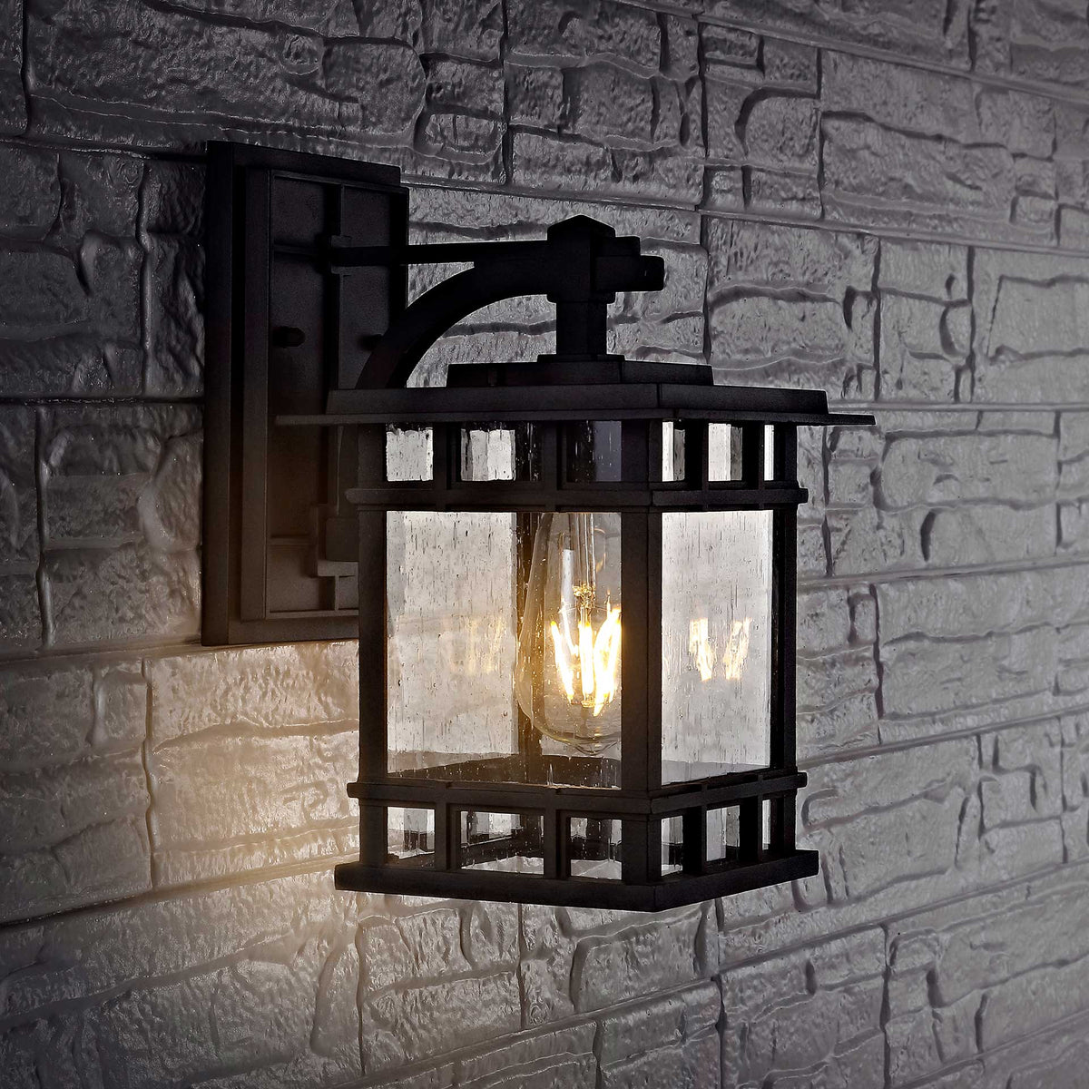 Warm light shines through clear glass panes framed by black metal and a curved wall bracket
