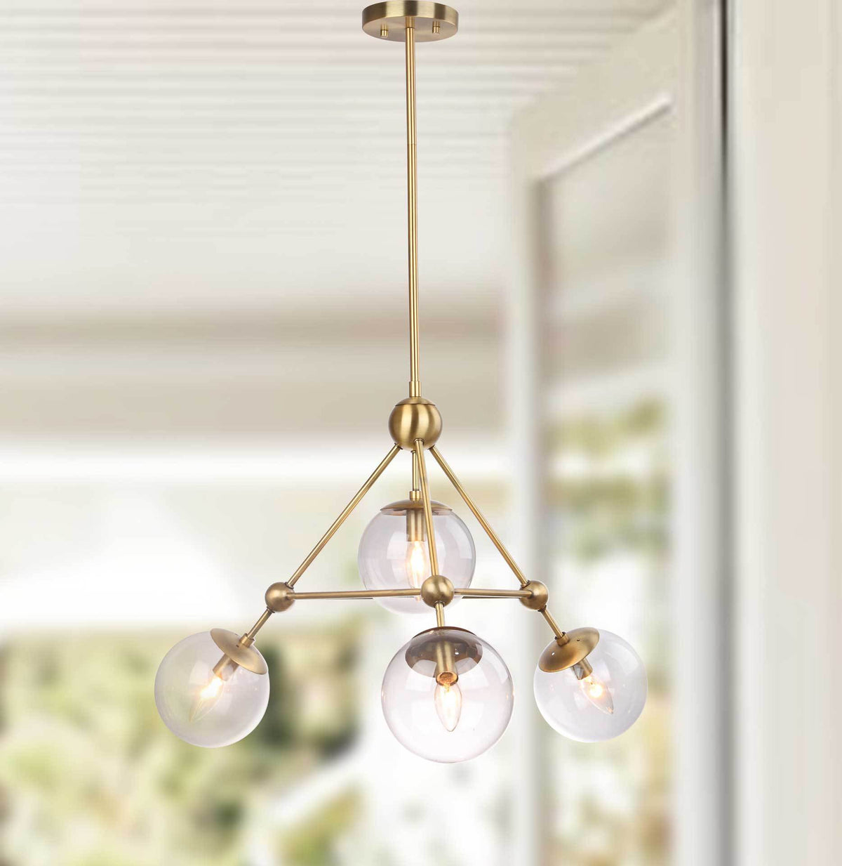Warm light glows from four clear glass globes beneath an airy gold-tone metal frame