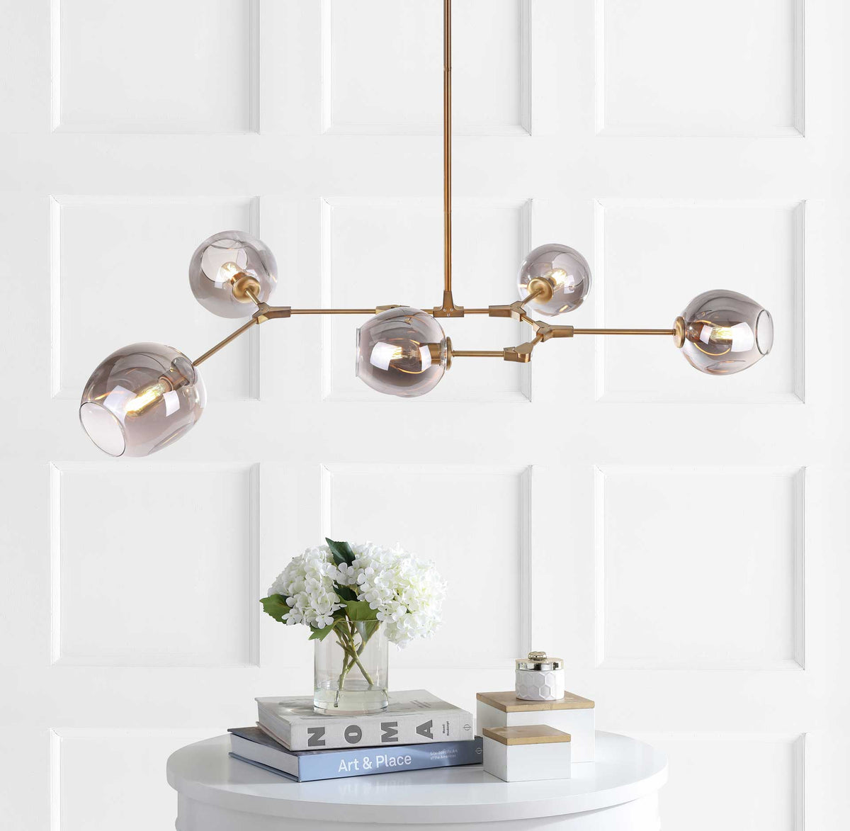 Five glowing glass globes give the brass-toned pendant a warm, modern presence.