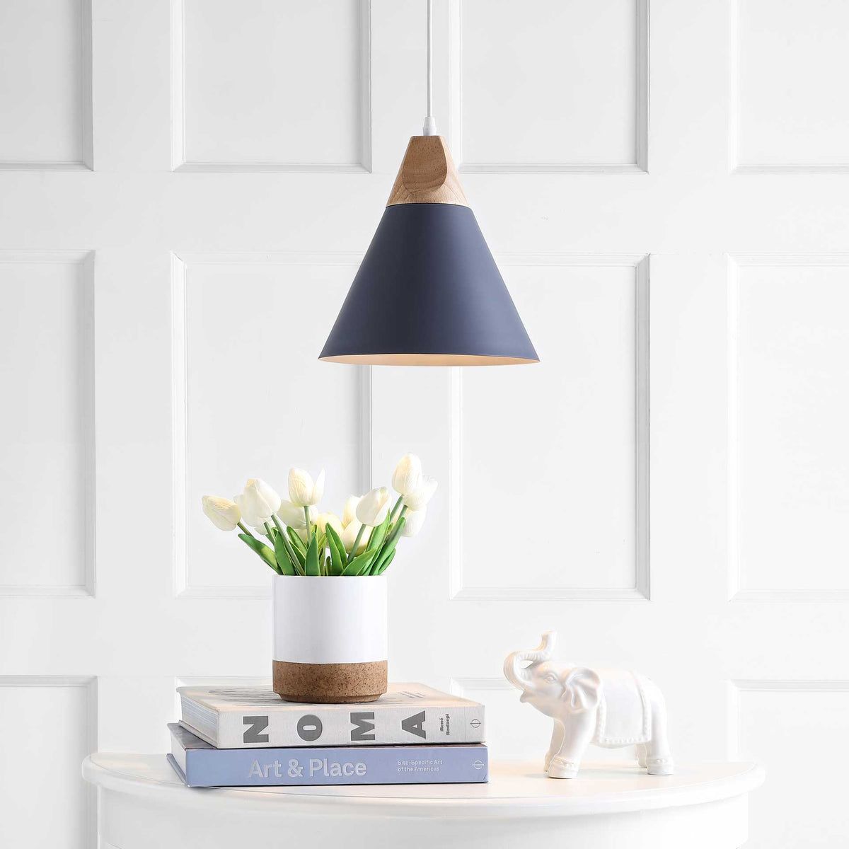 A soft glow from the dark gray cone shade warms flowers and a white console.