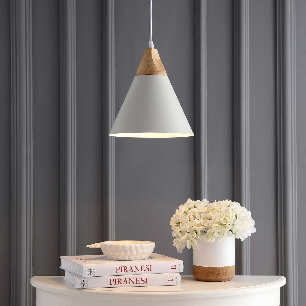 Warm downlight from a white cone shade illuminates flowers and a console.