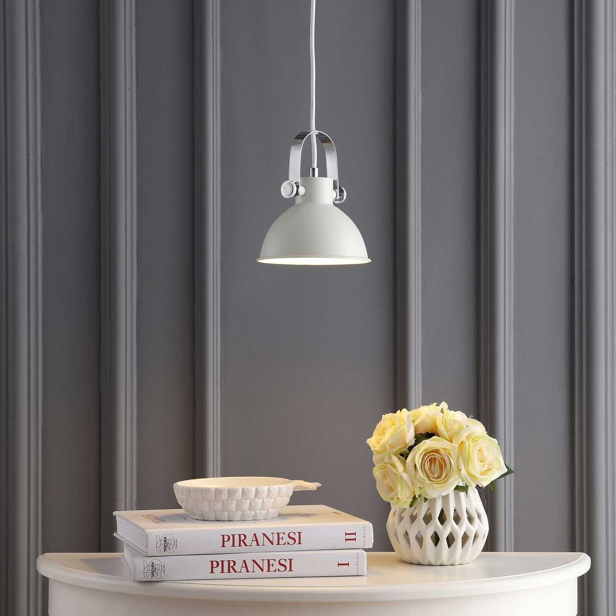A white metal dome brings warm illumination to a console with pale yellow roses