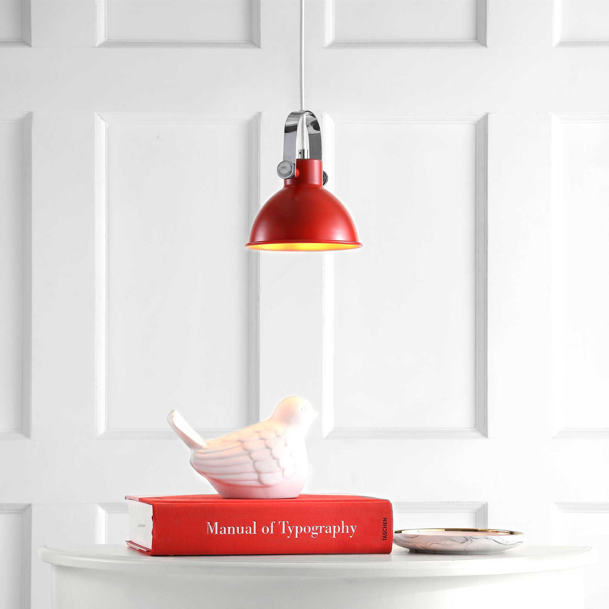 A red metal pendant lights the tabletop display with a warm downward glow