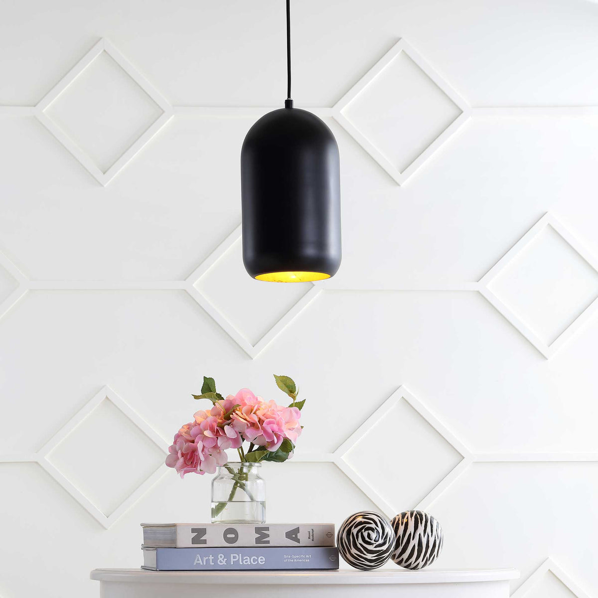 Warm downlight from a rounded black pendant brightens a console and floral arrangement