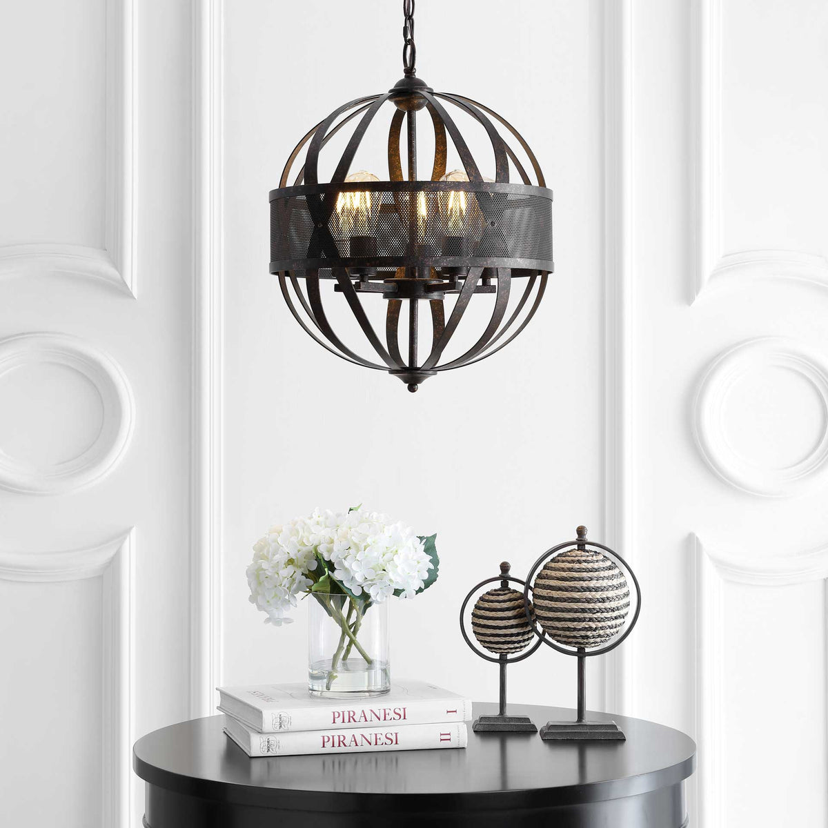 Warm light filters through a black metal orb pendant above a table with white flowers