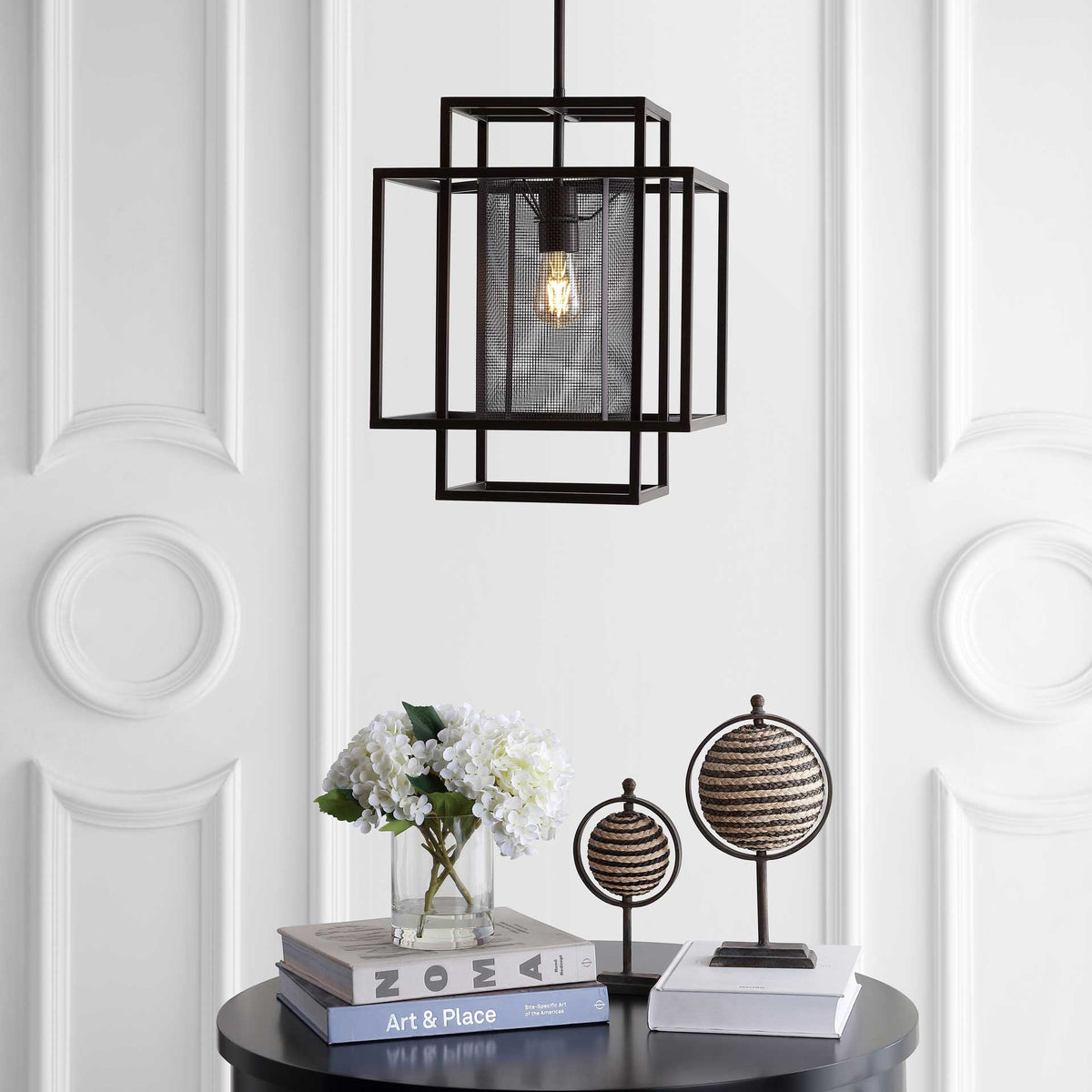 A softly glowing bulb lights the mesh center of a layered metal pendant above a table