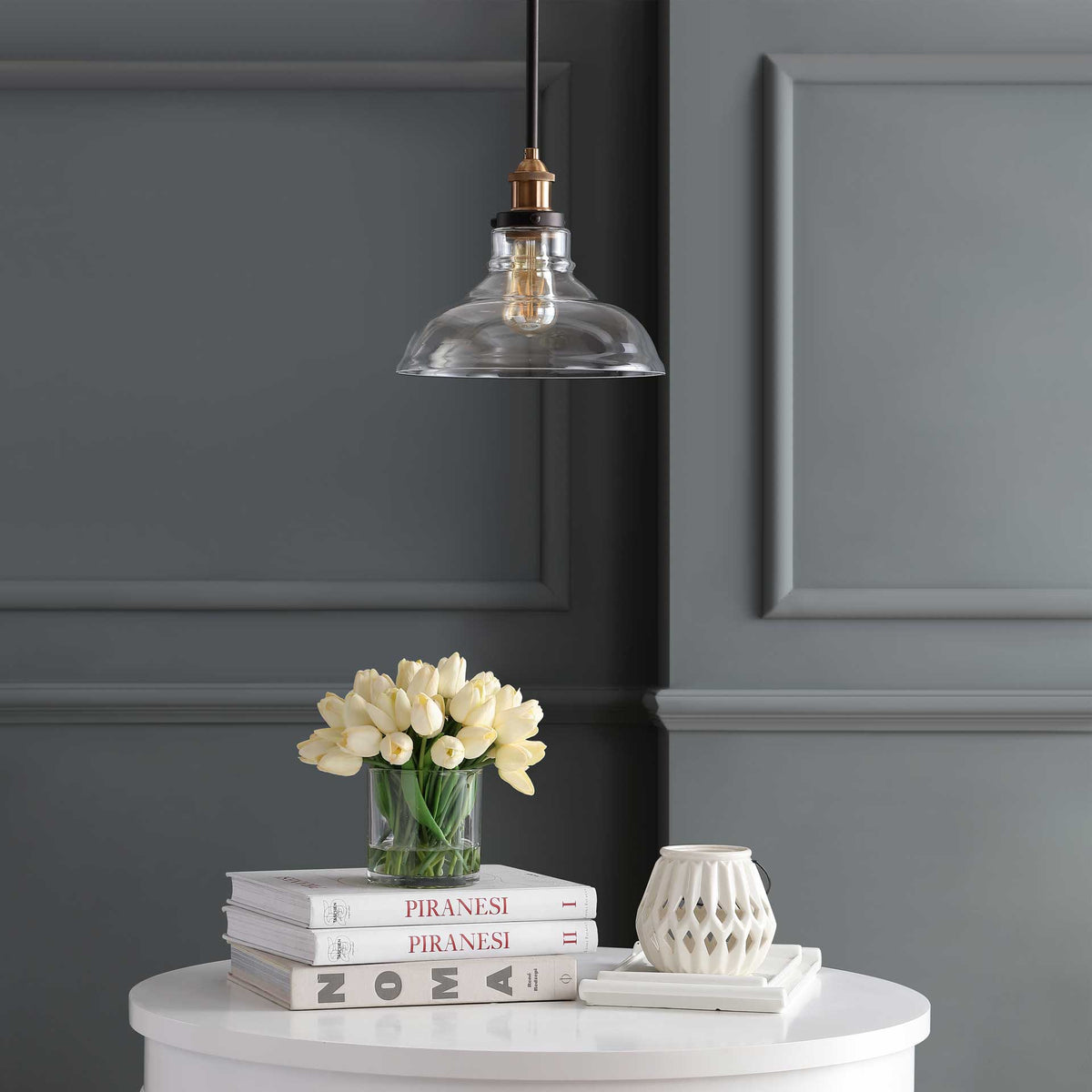 A clear glass shade reveals the bulb, brass-toned fittings, and slender dark rod.