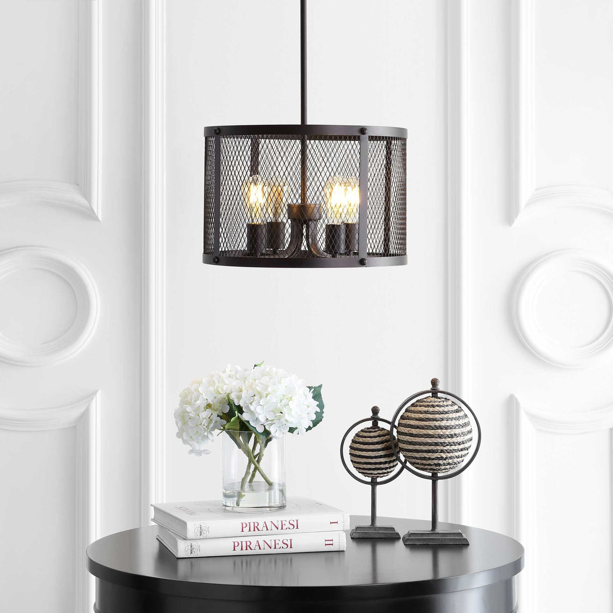 Warmly lit bulbs illuminate a dark metal mesh drum with an airy industrial look.