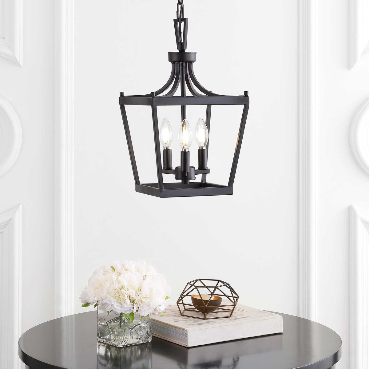 Three lit bulbs shine through the open bronze lantern frame