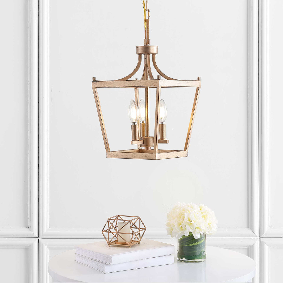 Warm light from three bulbs shines through the airy gold lantern frame