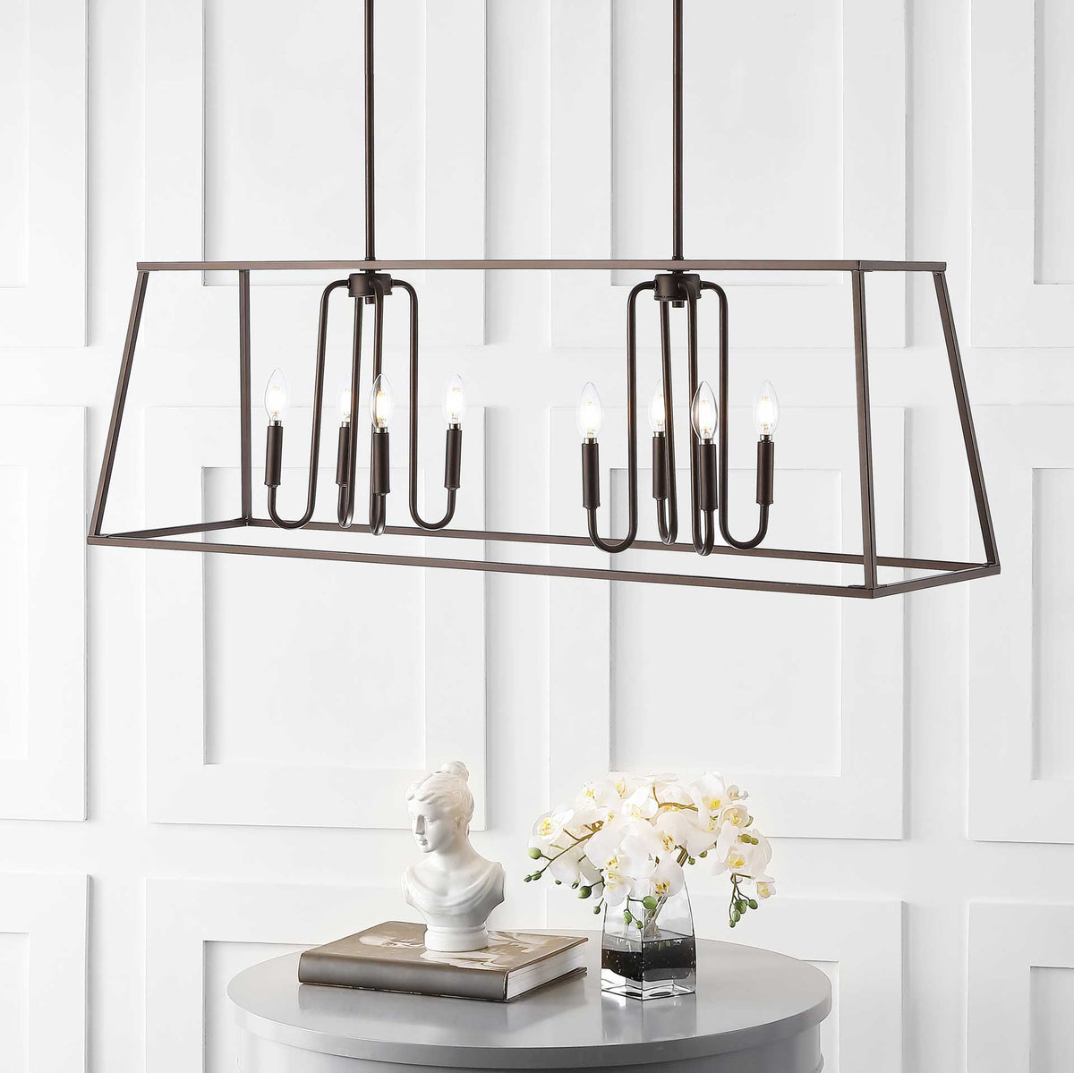 Glowing candle-style bulbs brighten the open bronze frame above a table with flowers.