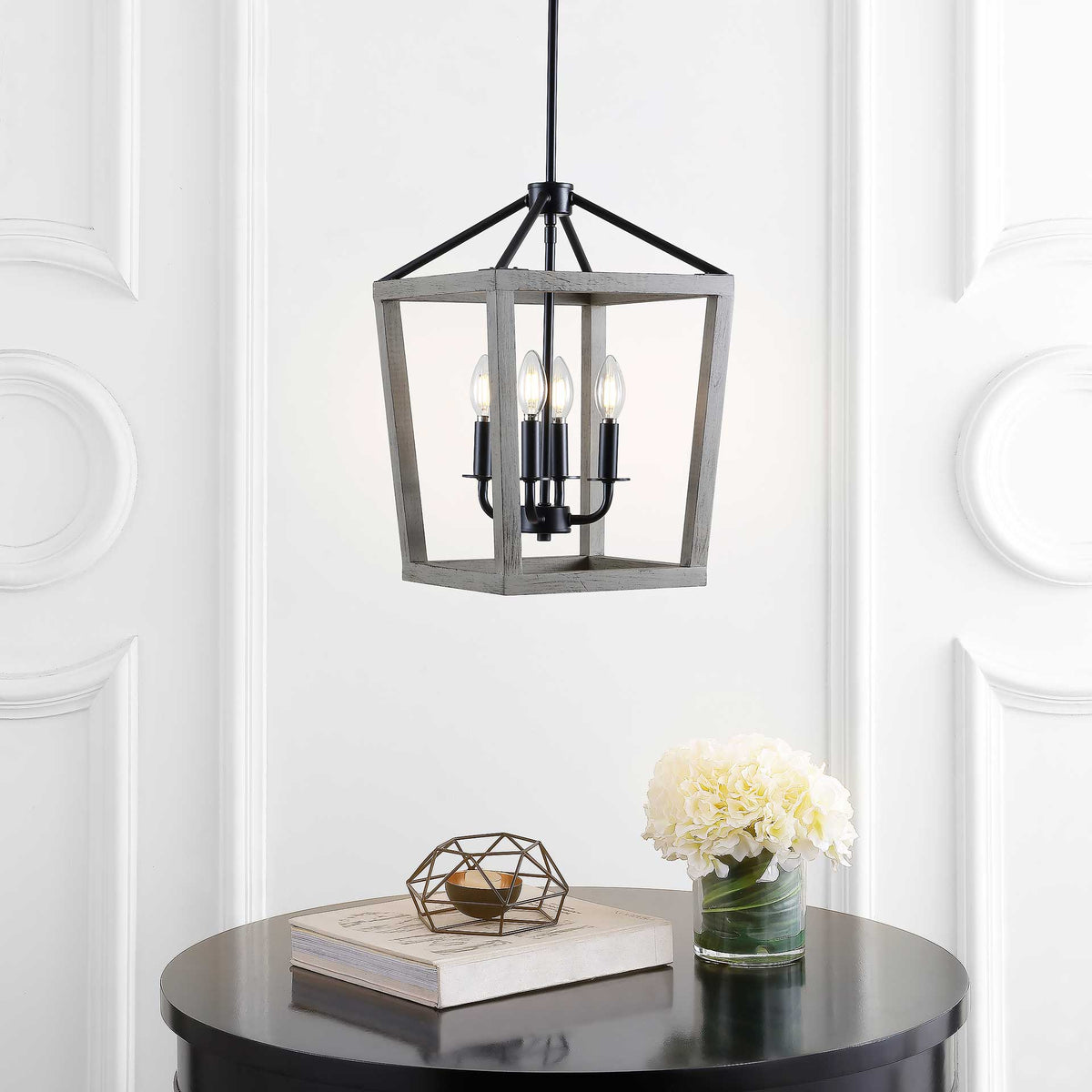 Warm light from four bulbs glows inside a rustic wood lantern frame above a dining table