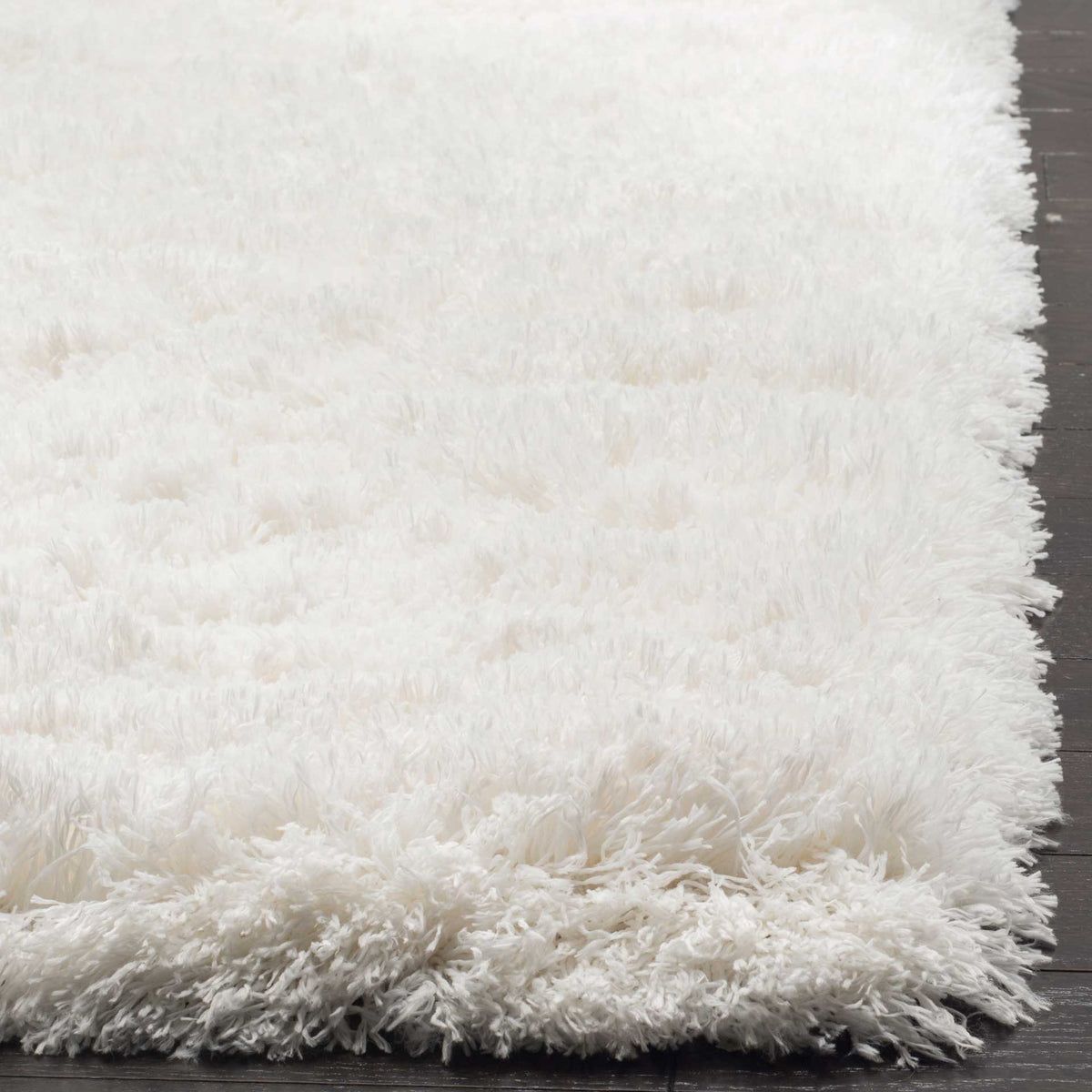 The white rug's thick, fluffy edge showcases its long, cushioned shag fibers.