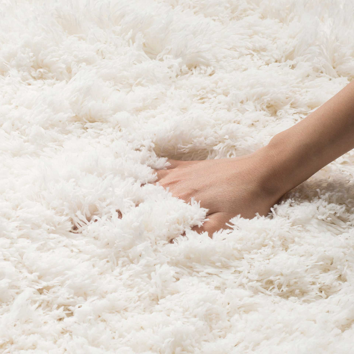 Fluffy white shag fibers yield softly to the touch for an inviting, sink-in feel.