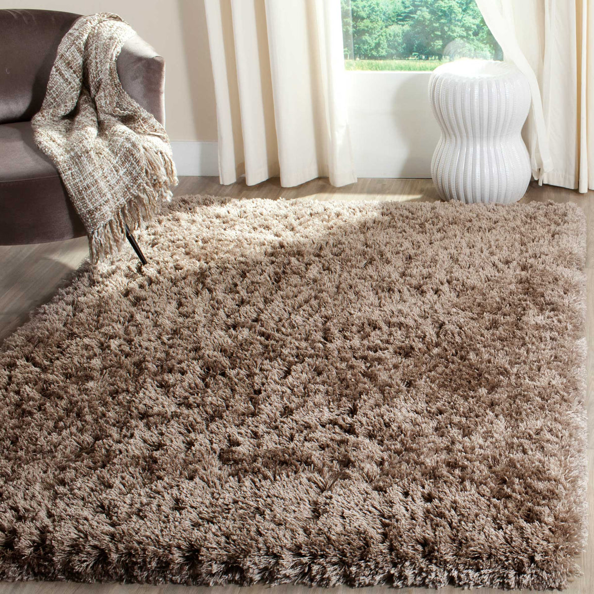 A plush mushroom shag rug lends earthy warmth and cushioned texture beside a lounge chair.
