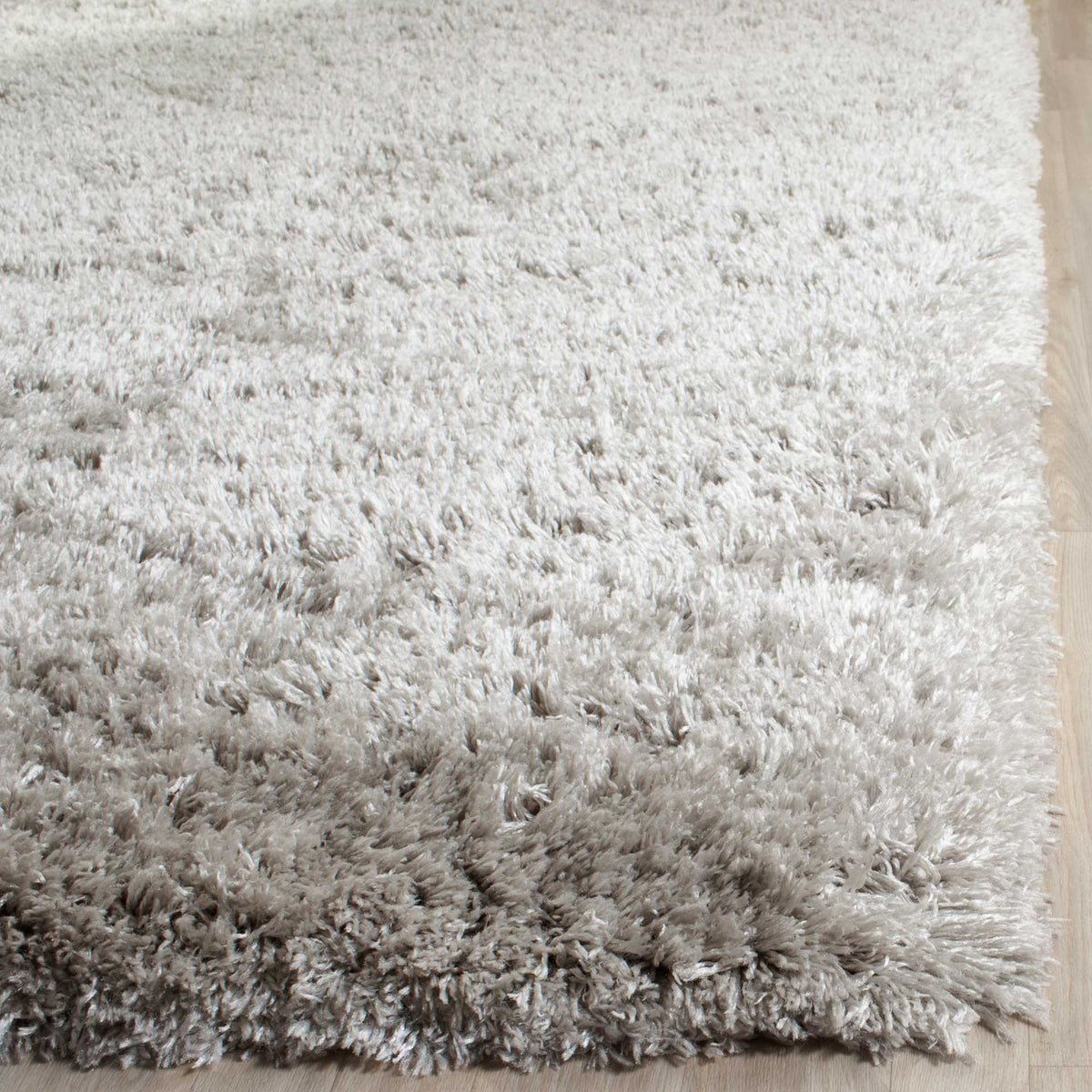 The silver rug's thick edge shows off its long, lustrous shag fibers.