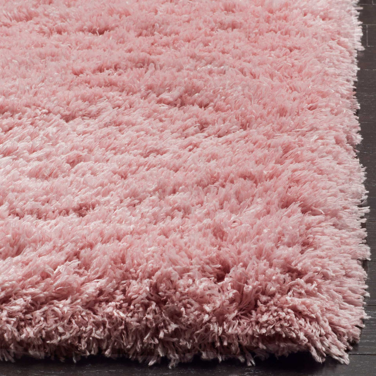 The light pink rug's thick edge reveals full, fluffy fibers and a soft finish.