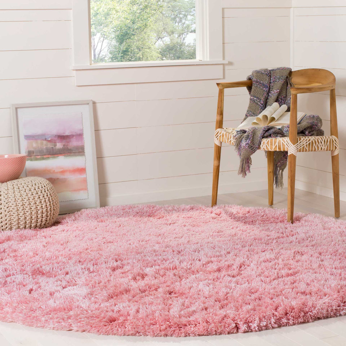 A plush pink round rug adds warmth beneath a wooden accent chair
