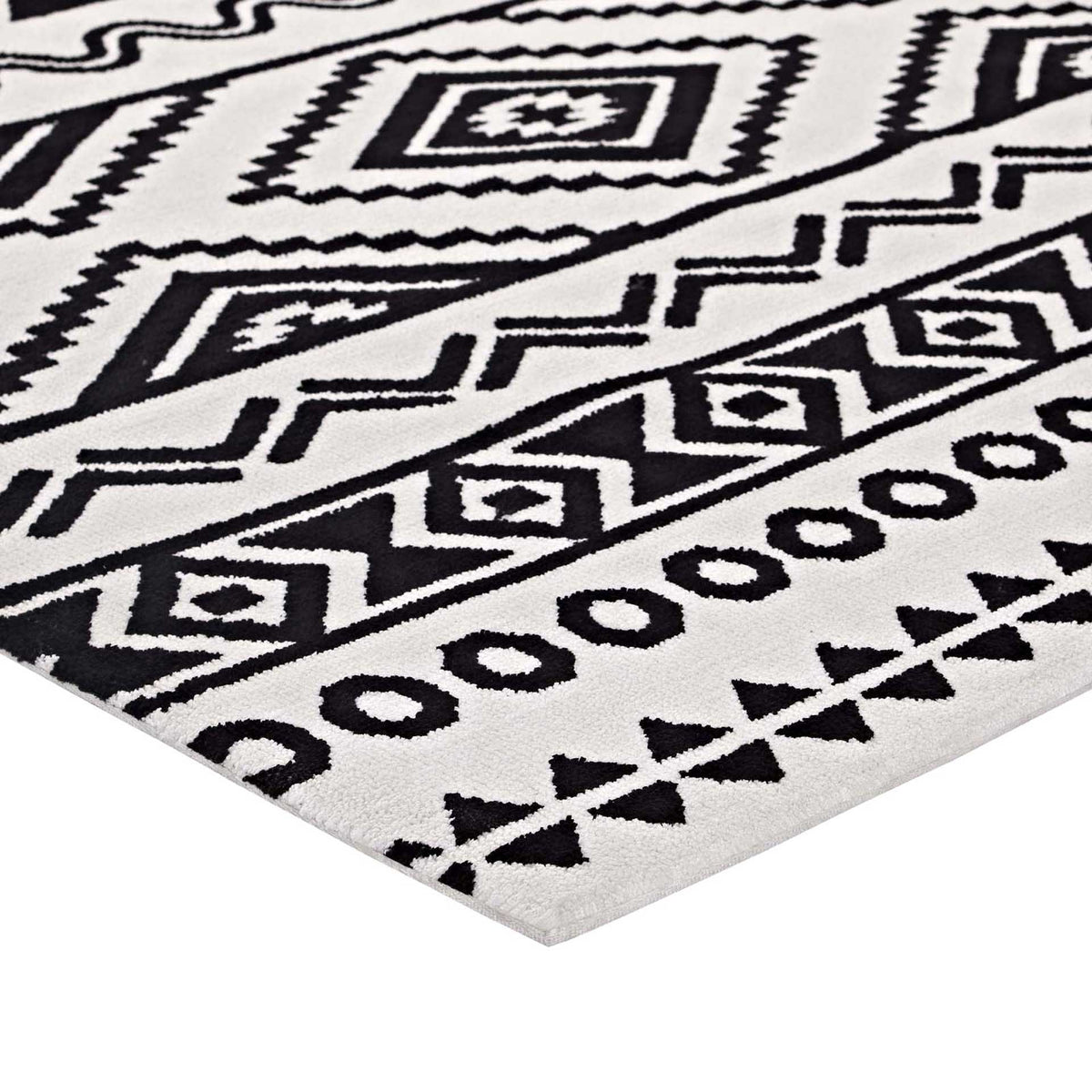 A neatly finished corner highlights bold diamond motifs and geometric borders on soft white pile.
