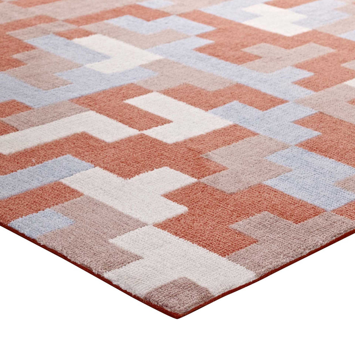 A soft, low-pile mosaic in coral and light blue meets a neatly finished rug edge.
