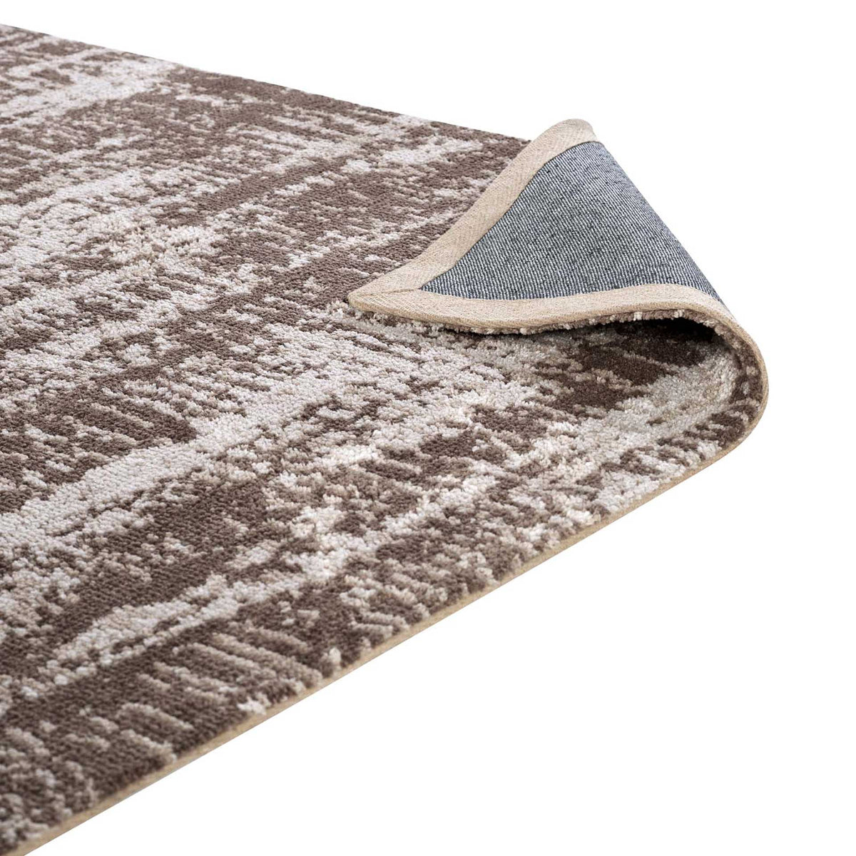 A turned-back corner reveals woven backing and a bound edge beneath the soft patterned pile.