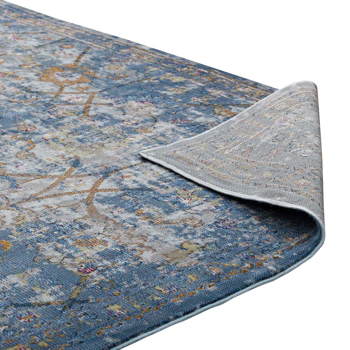 A pale woven underside supports the softly distressed blue-gray floral rug