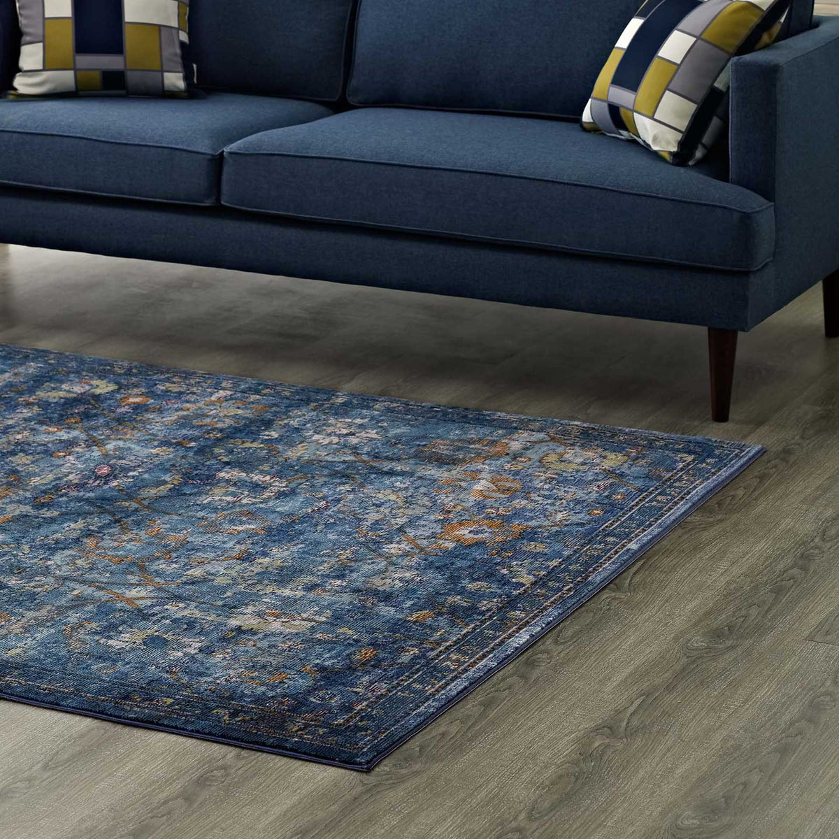 A deep blue floral rug brings saturated color beneath a navy sofa