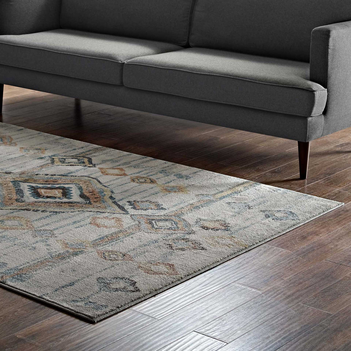Blue and rust diamond motifs lend color and texture beneath a charcoal sofa