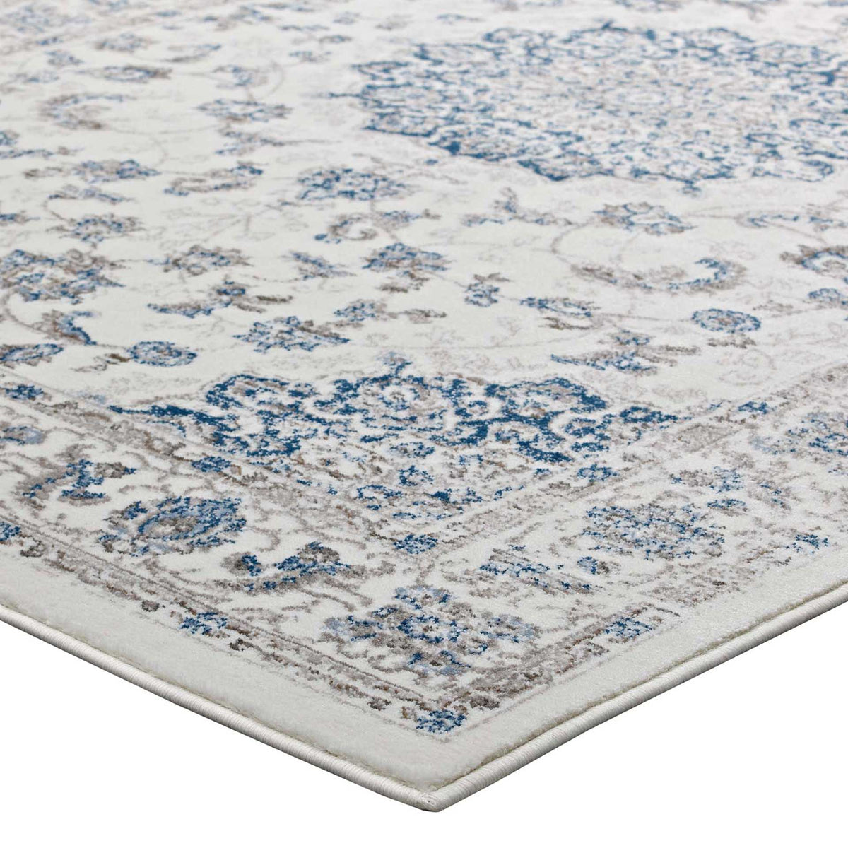A low-pile ivory rug features faded blue florals and a neatly bound edge