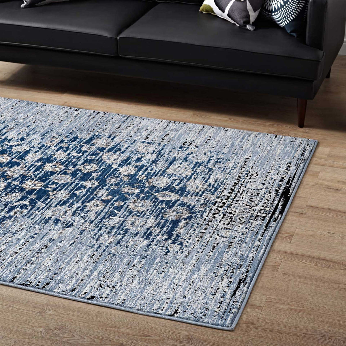 Distressed navy florals bring rich contrast to the pale blue rug beneath a dark sofa.