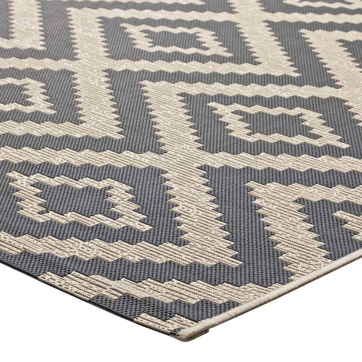 A bound edge finishes the rug's gray and beige geometric pattern and tight weave