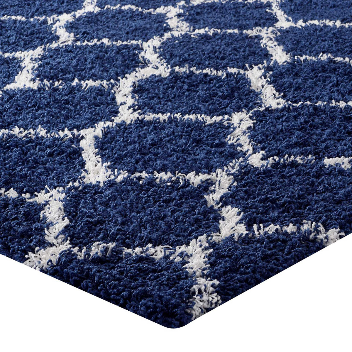 Ivory lattice lines rise through plush navy shag along a finished rug corner