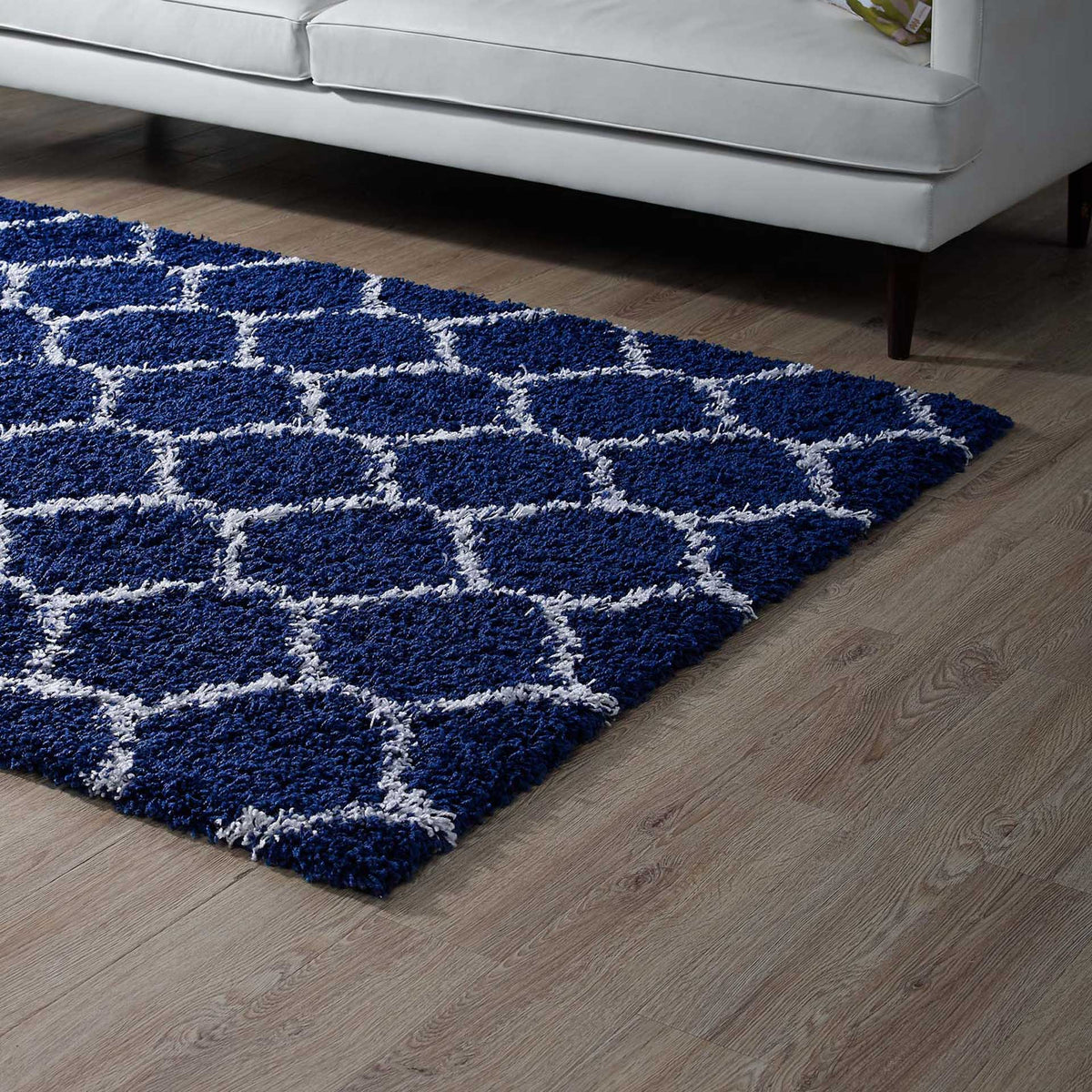 Deep navy trellis shag adds a bold patterned layer beside a white sofa