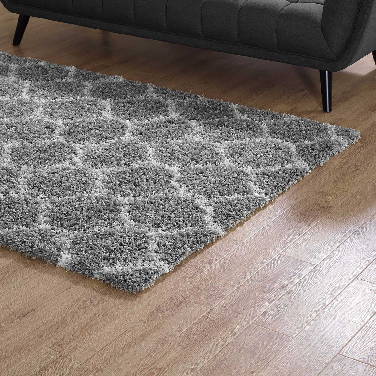 Thick gray trellis shag warms a wood floor beside a dark sofa