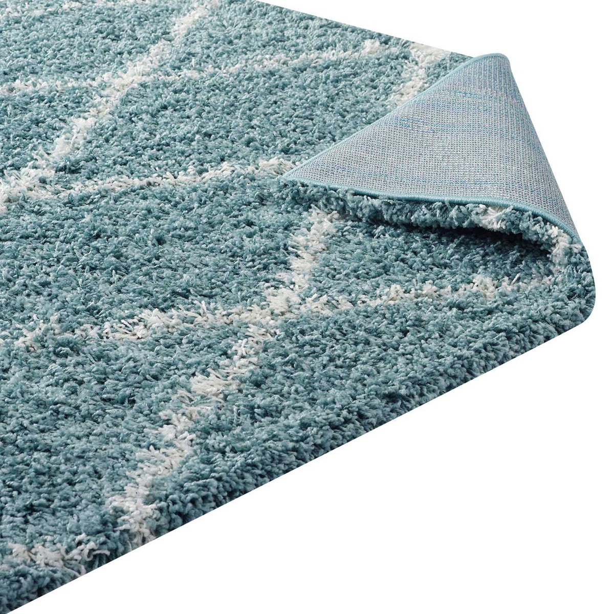 A woven backing supports thick aqua blue shag and its soft ivory diamond pattern.