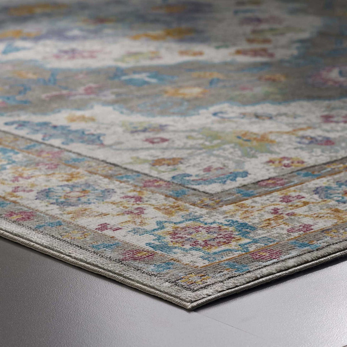 The bound gray edge outlines multicolored blooms along the distressed border