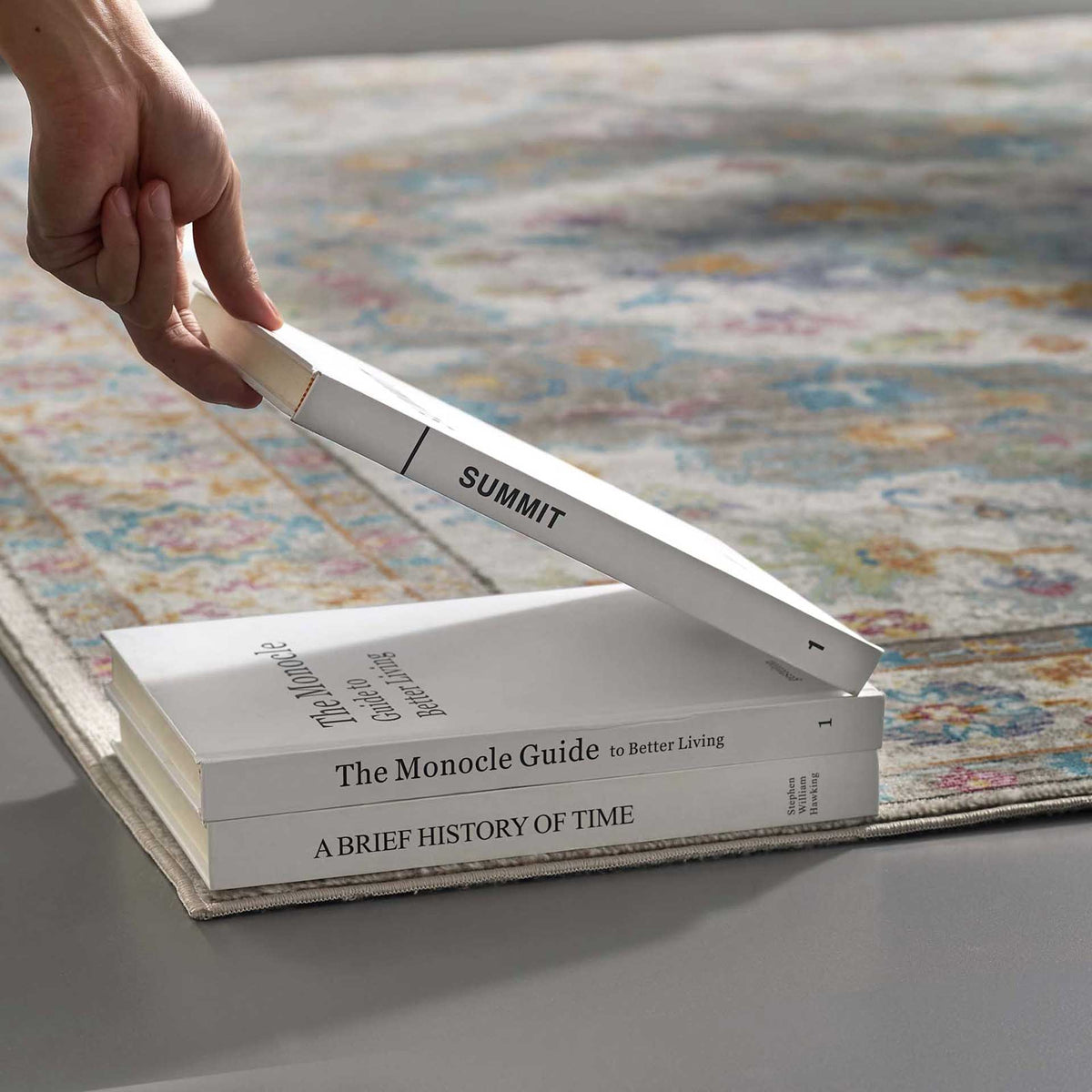 Low-profile gray floral weaving creates a smooth surface beneath stacked books