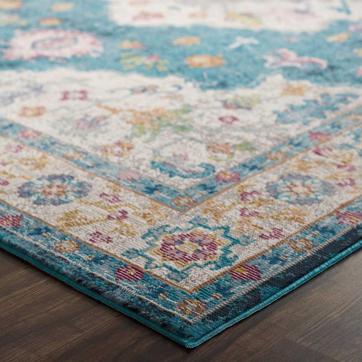 A vivid teal border and ivory floral motifs bring color to the rug's bound edge