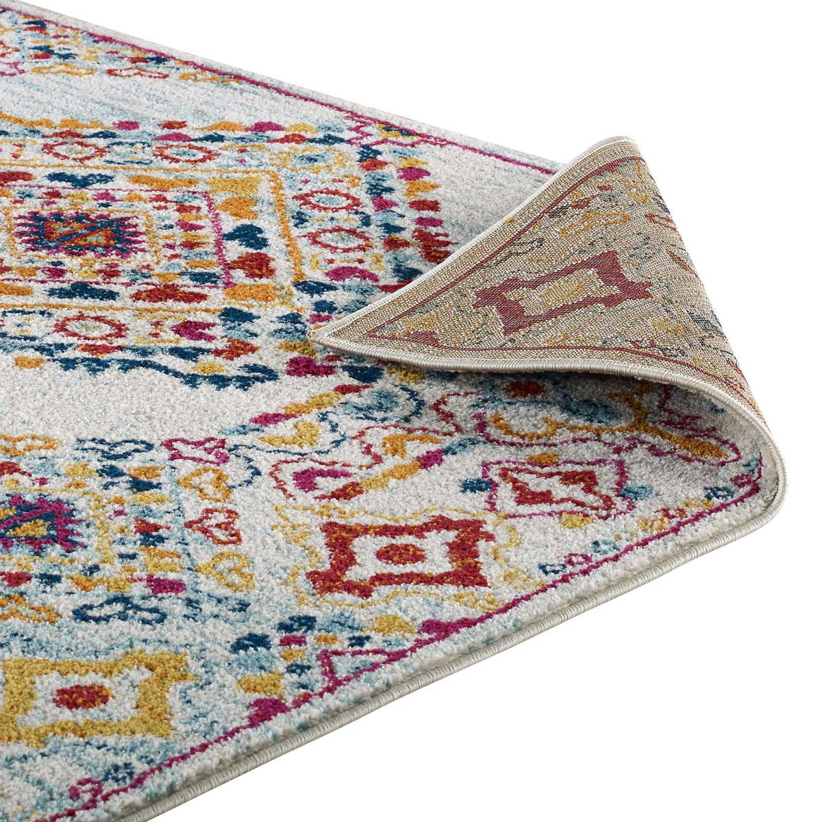 A folded corner reveals textured backing beneath the rug's colorful low-pile design.