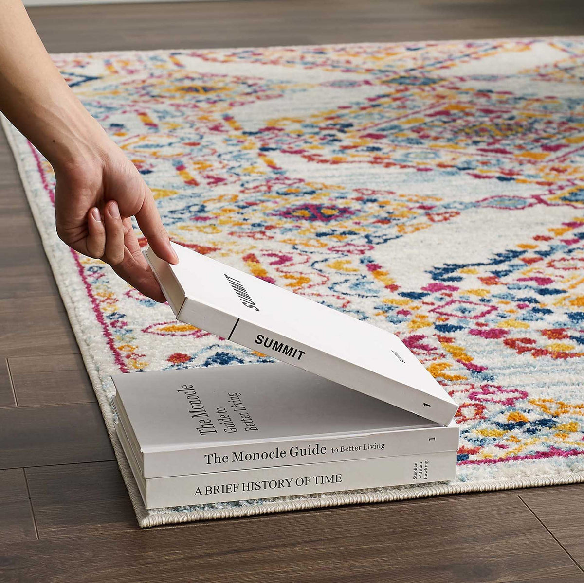Colorful medallions and a low, dense pile provide a smooth surface beneath stacked books.